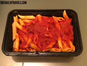 a black container with pasta and sauce
