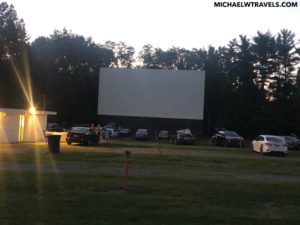 a large white screen in a field with cars parked in front of it