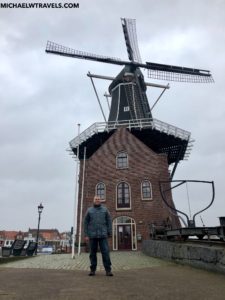 a man standing in front of a windmill