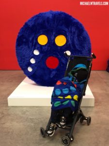 a baby in a stroller next to a large blue object