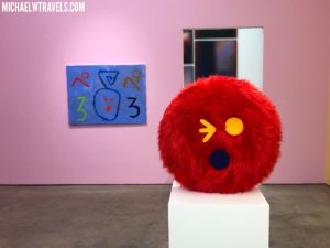 a red round object with yellow dots and a blue painting on the wall