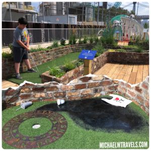 a boy playing golf in a miniature golf course