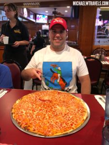 a man pointing at a pizza