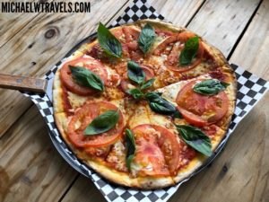 a pizza with tomatoes and basil on a black and white checkered napkin