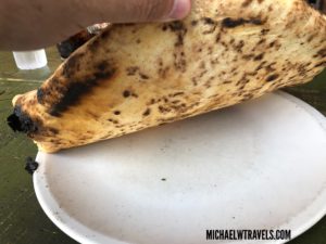 a hand holding a tortilla on a plate