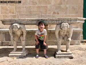 a boy standing in front of stone statues