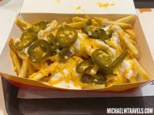 a box of french fries with jalapenos and cheese