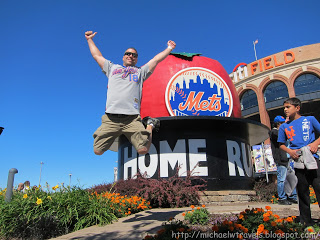 a man jumping in the air in front of a large statue of a baseball team