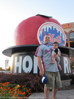 a man holding a baby in front of a large statue