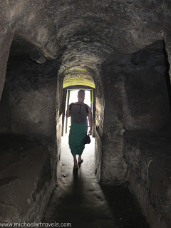 a person walking through a stone tunnel