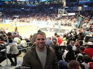 a man sitting in a stadium with a basketball court and a crowd