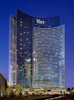 a tall building with many windows with Vdara in the background
