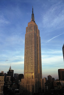 a tall building with a spire with Empire State Building in the background