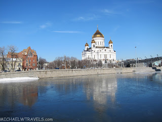 a white building with gold domes and a body of water
