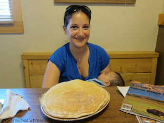 a woman sitting at a table with a large pancake