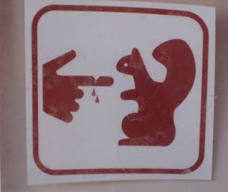 a sign with a finger pointing at a squirrel
