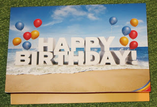 a birthday card with balloons on the beach