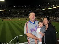 a man and woman holding a baby in a baseball stadium
