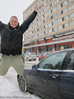 a man jumping in the air in front of a car
