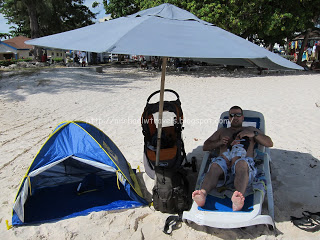a man lying on a beach chair under a umbrella