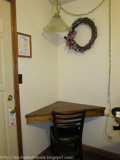 a corner table with a chair and a wreath on the wall