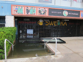 a flooded restaurant entrance with a metal fence