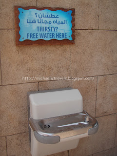 a water fountain with a sign on the wall