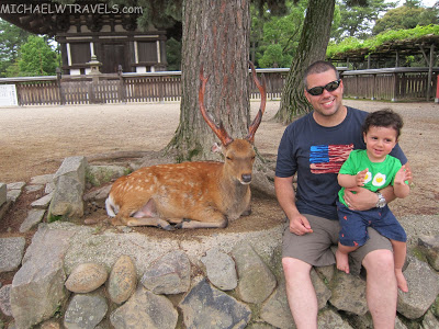 a man and child sitting next to a deer