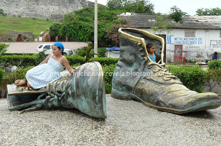 a girl sitting on a statue of a shoe