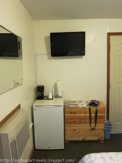 a small refrigerator and a tv on the wall