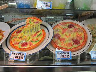 a couple of pizzas on plates with price tags