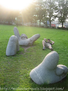 a man lying on grass next to a statue