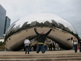 a man jumping in front of a reflective bean with Millennium Park in the background