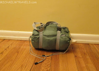a green duffel bag on a wood floor