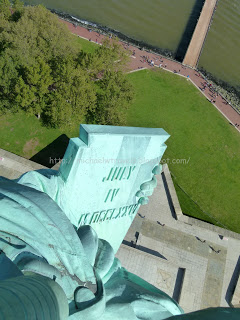 a statue of liberty with a green lawn and a water body