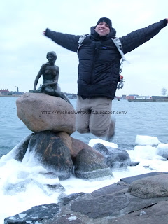 a man jumping in the air with a statue of a mermaid
